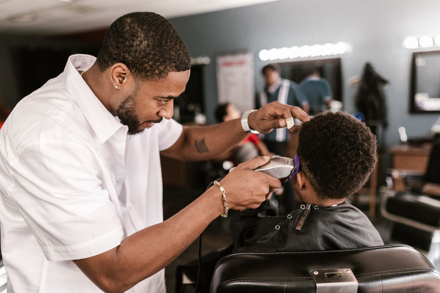 A barber giving a young boy a clipper cut in the chair
