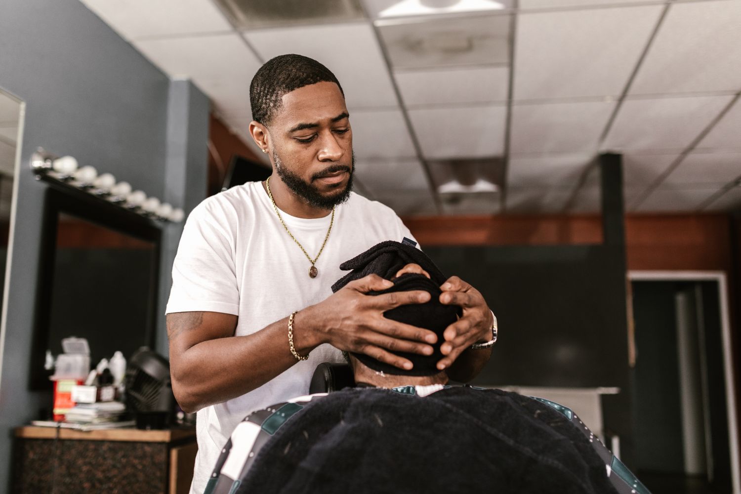 A barber giving a client a scalp and towel massage in the chair
